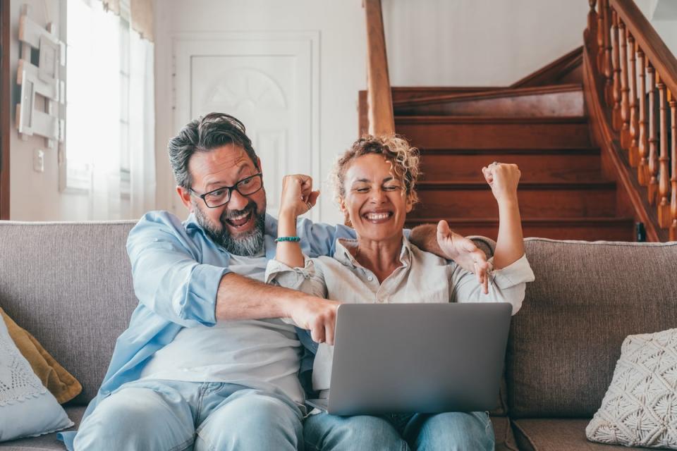 Two people celebrating while looking at a laptop.