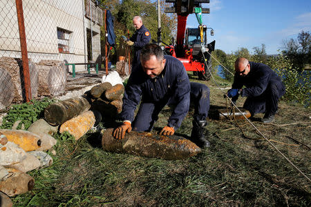 A deminer of a bomb-disposal unit moves an unexploded shell recovered in the Meuse River at Sivry-sur-Meuse, close to WWI battlefields, near Verdun, France, October 23, 2018 before the centenial commemoration of the First World War Armistice Day. REUTERS/Pascal Rossignol