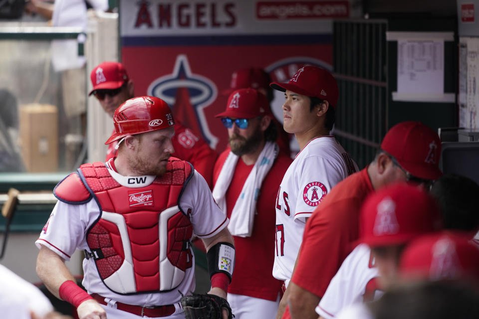 Los Angeles Angels catcher Chad Wallach, left, walks through the dugout past Shohei Ohtani, of Japan, during the first inning of a baseball game against the Houston Astros, Sunday, Sept. 4, 2022, in Anaheim, Calif. (AP Photo/Jae C. Hong)