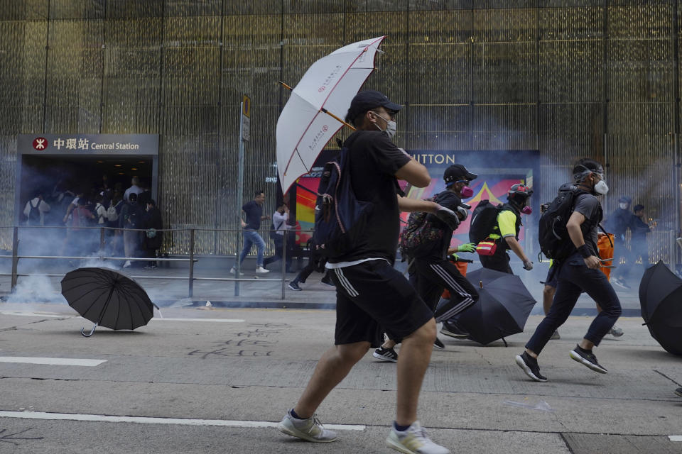 Pro-democracy protesters and people run away from tear gas fired by riot police during a rally in Central in Hong Kong, Tuesday, Nov. 12, 2019. Police fired tear gas at protesters who littered streets with bricks and disrupted morning commutes and lunch breaks Tuesday after an especially violent day in Hong Kong's five months of anti-government demonstrations. (AP Photo/Vincent Yu)