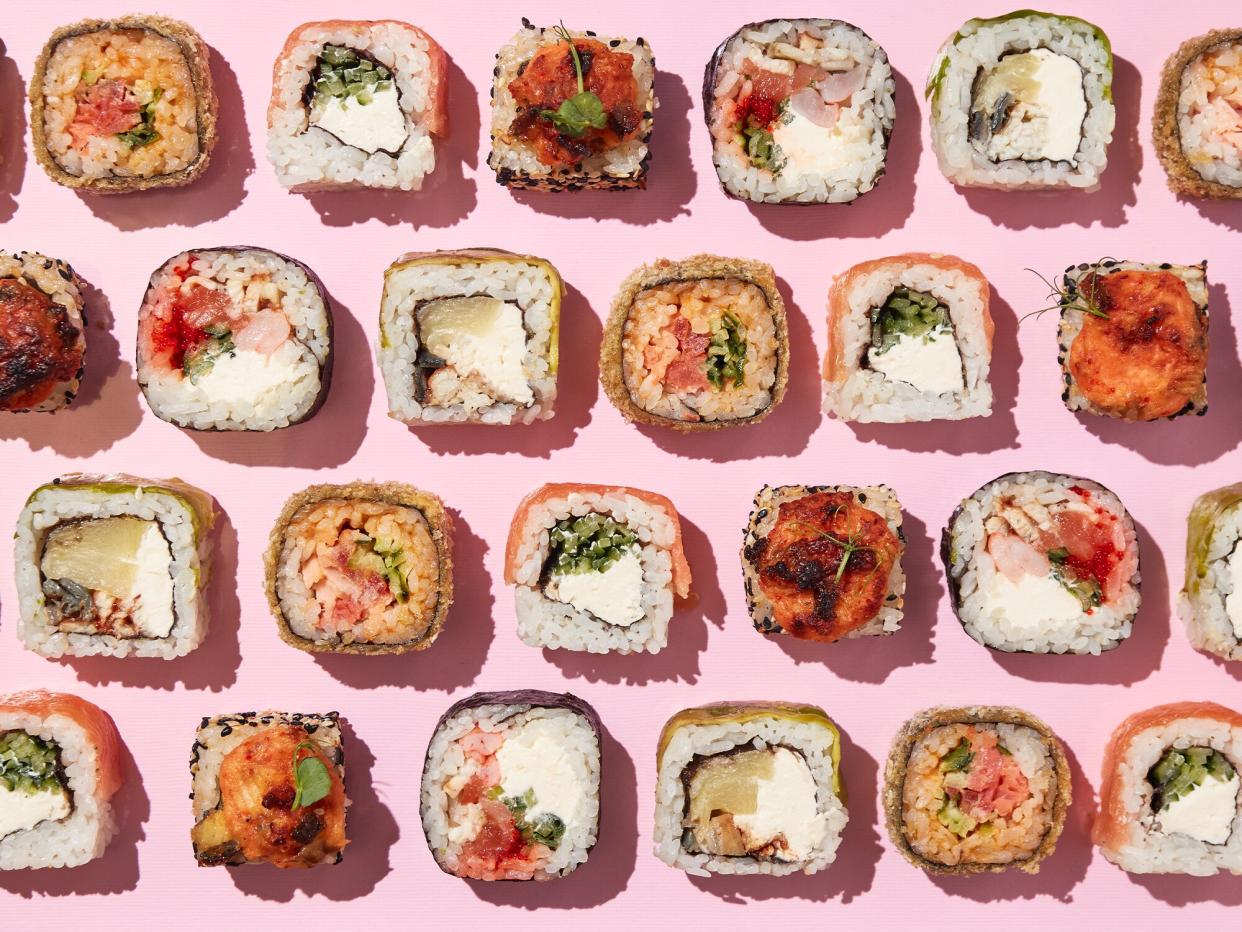 overhead of multiple pieces of sushi rolls on a pink background