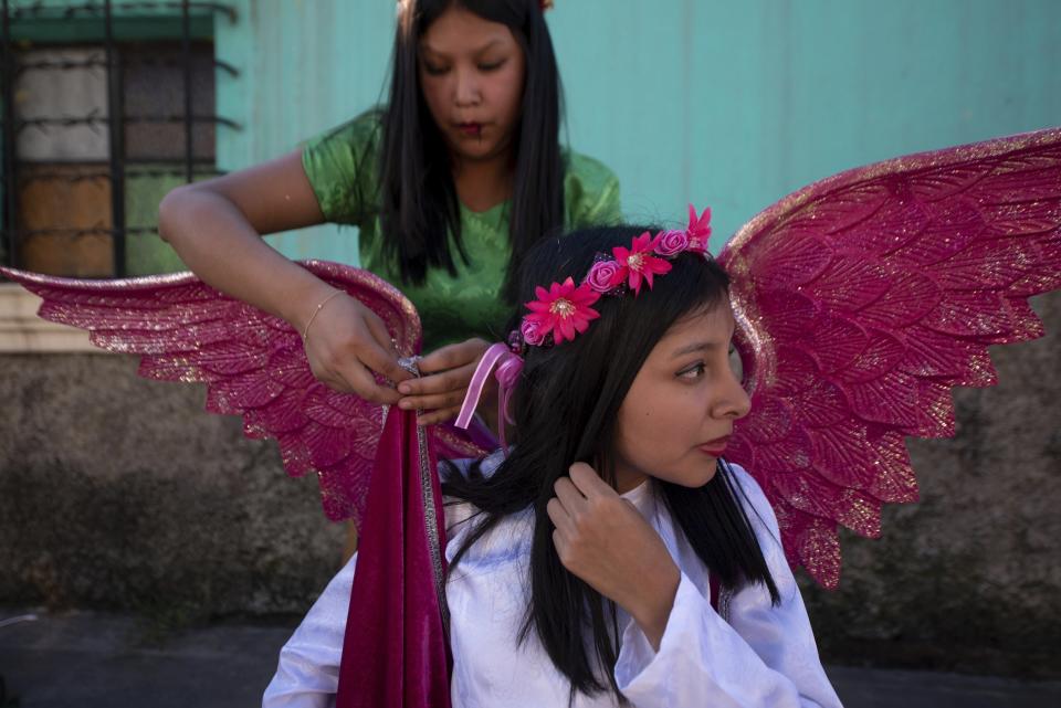Jennifer Lopez, top, and her sister Jessica adjust their angel costumes prior to a procession symbolizing the fight between good and evil to celebrate the Virgin of the Immaculate Conception in Ciudad Vieja, Guatemala, Friday, Dec. 7, 2018. Catholics hold their neighbor days-long annual fair in honor of their patron saint, the Virgin of the Immaculate Conception, whose official feast day is Dec. 8. (AP Photo/Santiago Billy)
