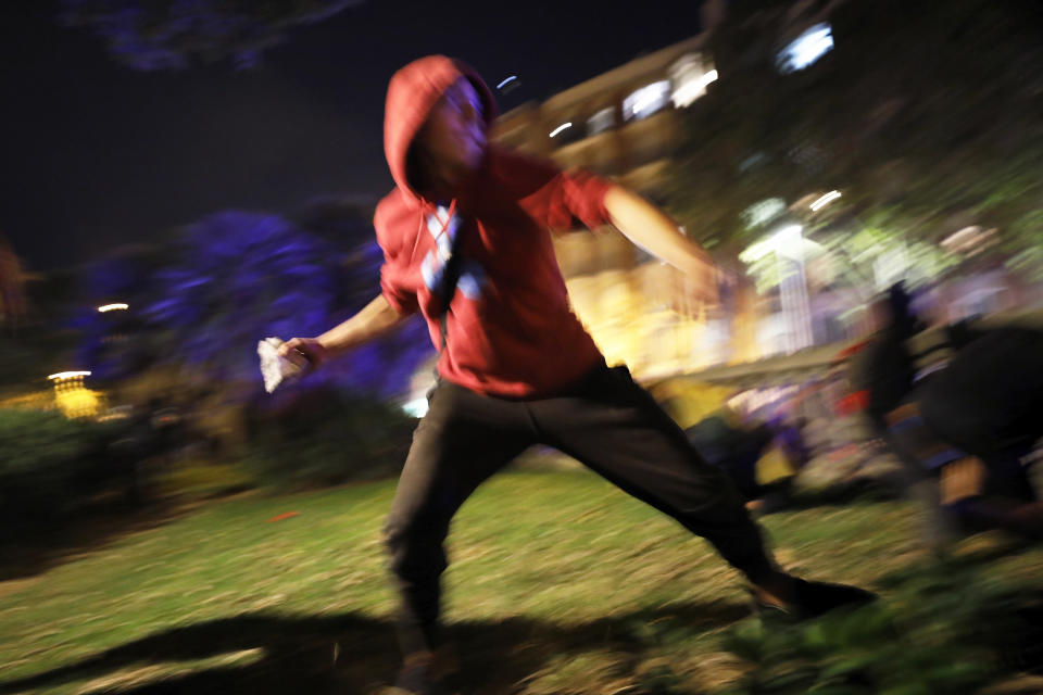 A protestor hurls a rock at police during clashes in Barcelona, Spain, Wednesday, Oct. 16, 2019. Spain's government said Wednesday it would do whatever it takes to stamp out violence in Catalonia, where clashes between regional independence supporters and police have injured more than 200 people in two days. (AP Photo/Emilio Morenatti)