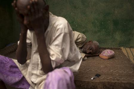 A man rests on a mat as another washes his face prior to prayers near a mosque some distance from Kilometre 12 (PK12) where internally displaced Muslims are stranded due to the ongoing sectarian violence in Bangui March 6, 2014. REUTERS/Siegfried Modola