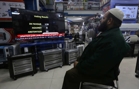 A Palestinian man watches a televised broadcast of the U.N. General Assembly vote on a draft resolution calling on the United States to withdraw its recognition of Jerusalem as Israel's capital, at an electrical appliances store in Rafah in the southern Gaza Strip December 21, 2017. REUTERS/Ibraheem Abu Mustafa