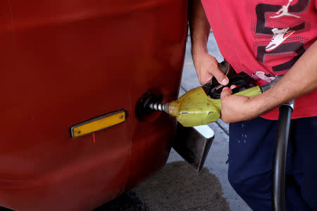 A man pumps gas into his car at a gas station of the Venezuelan state-owned oil company PDVSA in Caracas, Venezuela August 17, 2018. REUTERS/Marco Bello