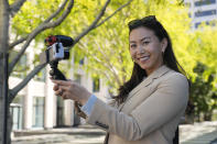 Content creator Cynthia Huang Wang poses near the Embarcadero in San Francisco, Monday, April 8, 2024. Despite a strong job market, there are still thousands of people who have found themselves out of work across industries stretching from tech to retail to media. But rather than trying to find another job in their old role, some workers are turning to online content creation. (AP Photo/Eric Risberg)