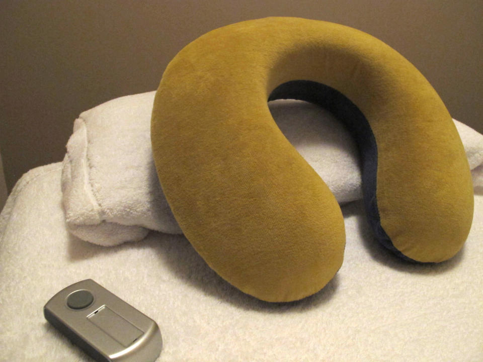 In this March 1, 2013 photo, a travel pillow and an alarm lay on a bed prepared for a client at "Espacio Siestario" where people can take a day time nap in Santiago, Chile. Clients enter windowless rooms lighted by a scented candle and lie down on a massage table cushioned by fresh white towels and sheets. With travel pillows hugging their necks, they get a five-minute massage on their arms, shoulders and head. Then the lights are dimmed and nearly imperceptible music helps them nod off as the world hurries along outside. (AP Photo/Luis Andres Henao)