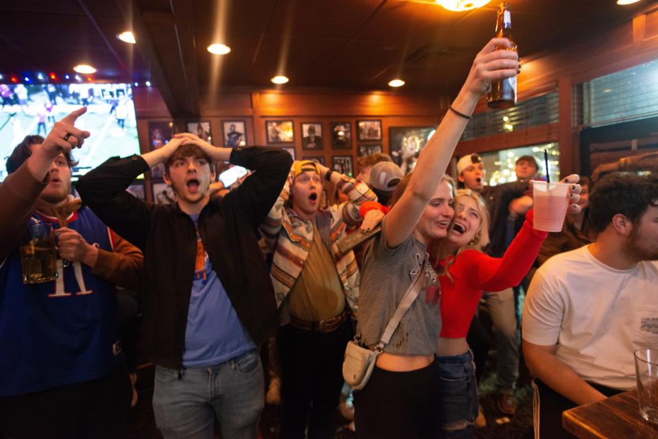 A few Arkansas football fans react alongside Kansas fans at Logie’s on Mass Street in Lawrence as the two teams battle into the third overtime for the Liberty Bowl.