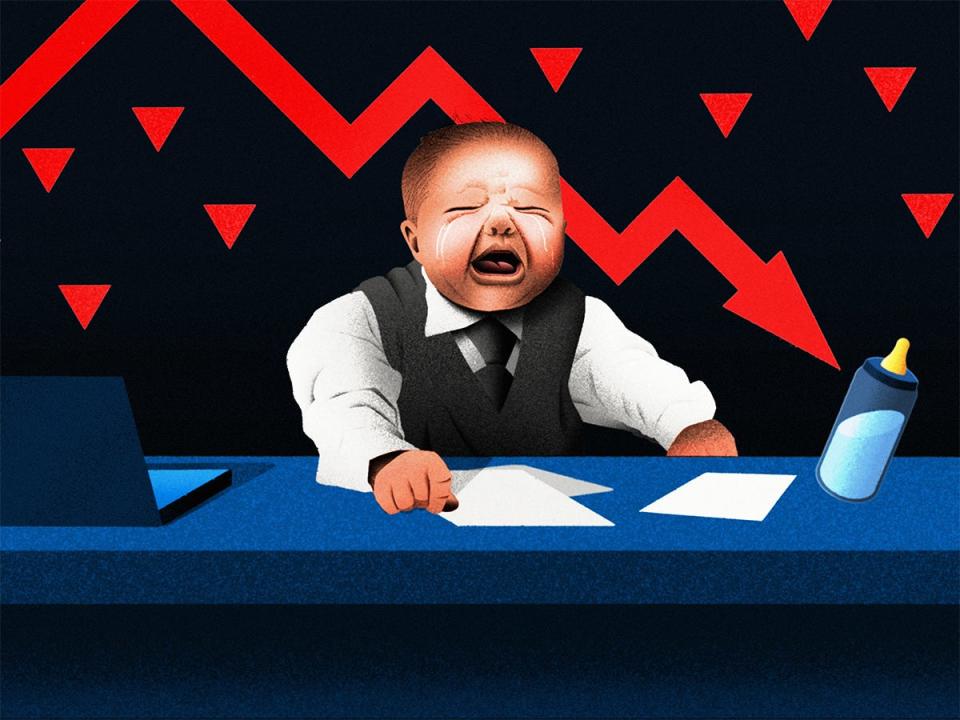 A baby in a suit representing young investment bankers on Wall street crying at a desk with a downward stocks arrow.