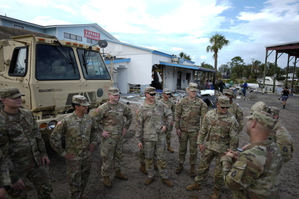 Members of the National Guard gather outside a storm-damaged business as they await the arrival of Florida Gov. Ron DeSantis, in Horseshoe Beach, Fla., Thursday, Aug. 31, 2023, one day after the passage of Hurricane Idalia. (AP Photo/Rebecca Blackwell)