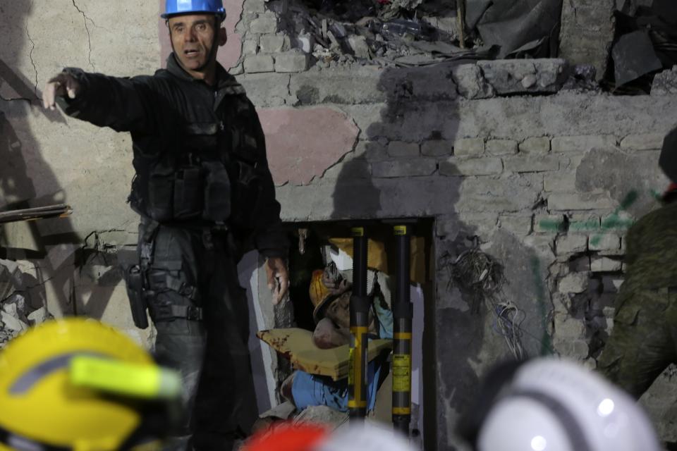 Rescuers try to free a man from a collapsed building after a magnitude 6.4 earthquake in Thumane, western Albania, Tuesday, Nov. 26, 2019. Rescue crews with excavators searched for survivors trapped in toppled apartment buildings and hotels Tuesday after a powerful pre-dawn earthquake in Albania killed at least 18 people and injured more than 600. (AP Photo/Visar Kryeziu)