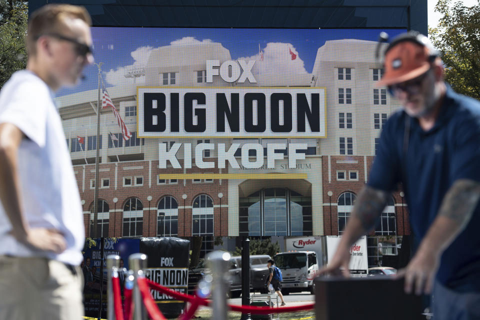 Workers, foreground, assemble a set for the Fox "Big Noon Kickoff" football show Sept. 16, 2022, at University of Nebraska Union in Lincoln, Neb. “College GameDay” has continued its reign as the preeminent pregame show leading into Saturday afternoon kickoffs. But the ESPN franchise goes into its 37th year with the most changes it has had going into a season as well as facing competition from Fox and its upstart “Big Noon Kickoff.” (Noah Riffe/Lincoln Journal Star via AP)