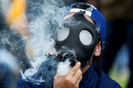 A man smoking marijuana through a mask during a Global March for marijuana in Bogota, Colombia, May 5, 2018. REUTERS/Jaime Saldarriaga
