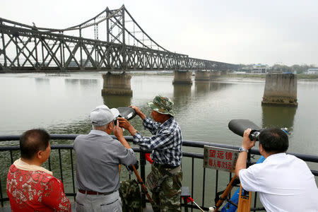 People look through binoculars towards North Korea from the destroyed bridge across Yalu River that once linked North Korea's Sinuiju and Dandong, China's Liaoning province, September 10, 2016. REUTERS/Thomas Peter/File Photo