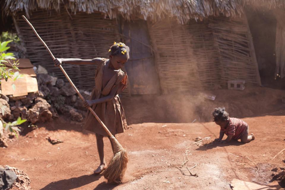 In this Tuesday, March 25, 2014 photo, Larionise Beltinor 10, sweeps the entrance of her home while her 7-month-old brother Jean Widson Beltimor crawls nearby in Bombardopolis, northwestern Haiti. Drought is hitting this region, one of the hungriest, most desolate parts of the most impoverished nation in the hemisphere. Officials hope to tide people over through the rainy season that is supposed to begin in April and until harvest in June. (AP Photo/Dieu Nalio Chery)