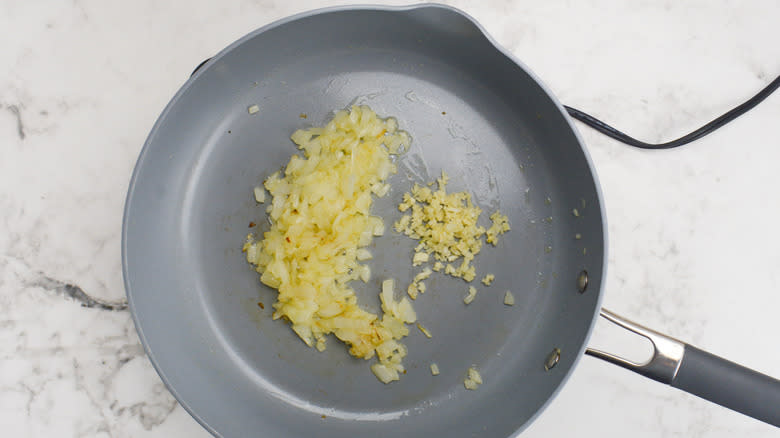 minced garlic sautéing with onion in pan