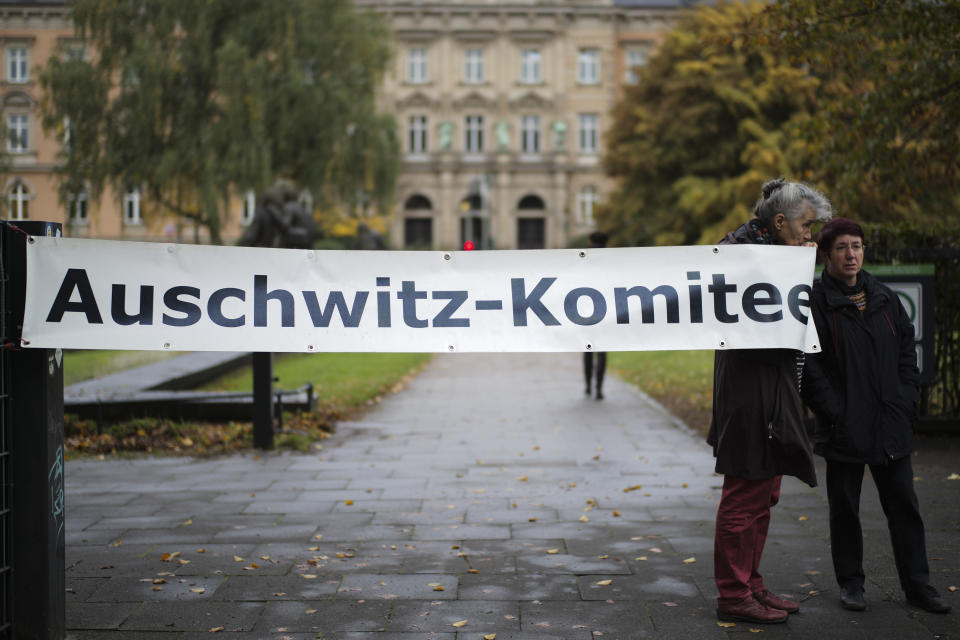 Two women of the Auschwitz Committee show a poster near the criminal court in Hamburg, Thursday, Oct. 17, 2019. 93-year-old former SS private Bruno Dey is going on trial at the court on 5,230 counts of being an accessory to murder, accused of helping the Nazis' Stutthof concentration camp function. (AP Photo/Markus Schreiber)