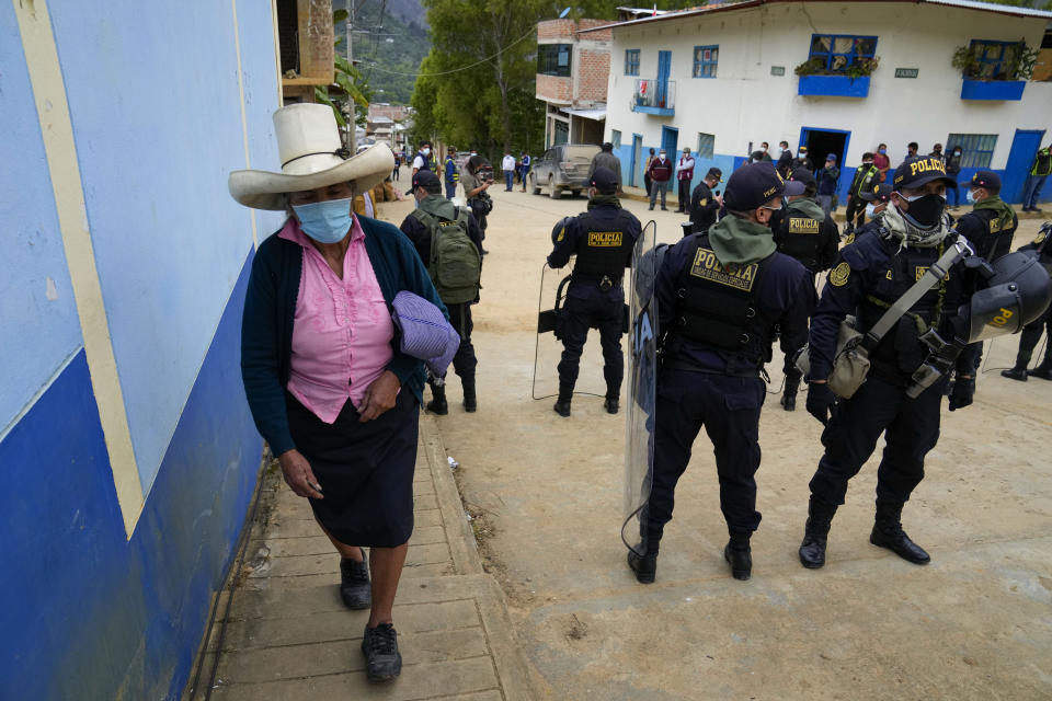 A voter arrives to a polling station guarded by police in Tacabamba, Peru, Sunday, June 6, 2021. Peruvians vote Sunday in a presidential run-off election to choose between Pedro Castillo, a political novice who until recently was a rural schoolteacher, and Keiko Fujimori, the daughter of jailed ex-President Alberto Fujimori. (AP Photo/Martin Mejia)