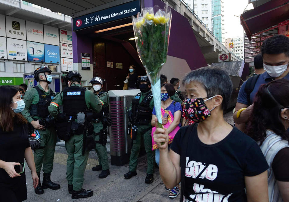 A woman holds flowers outside the Prince Edward subway station in Hong Kong Monday, Aug. 31, 2020. Aug. 31 is the first anniversary of police raid on Prince Edward subway station which resulted in widespread images of police beating people and drenching them with pepper spray in subway carriages. (AP Photo/Vincent Yu)