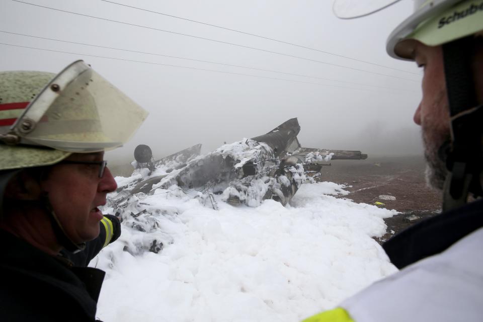 Firefighters stand next to the burnt-out wreckage of a twin-engine business jet near Foehren Germany, Sunday Jan . 12, 2014. Police say a small jet has crashed near an airfield in western Germany and four people on board are believed to have died. The plane came down Sunday lunchtime at a landfill site near the city of Trier. City police said in a statement that it appears to have been a Cessna Citation business jet carrying two pilots and two passengers from England to an airfield at Foehren, near the crash site. (AP Photo/dpa,Thomas Frey)