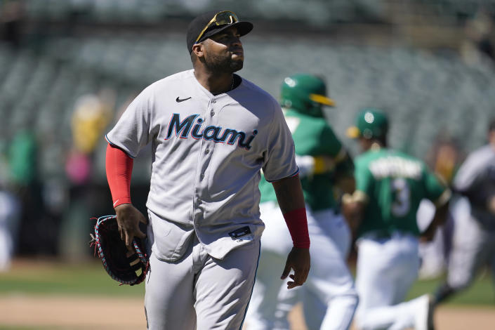 Miami Marlins first baseman Jesus Aguilar walks off the field as Oakland Athletics players celebrate after defeating the Marlins in a baseball game in Oakland, Calif., Wednesday, Aug. 24, 2022. The Athletics won, 3-2, in 10 innings. (AP Photo/Jeff Chiu)