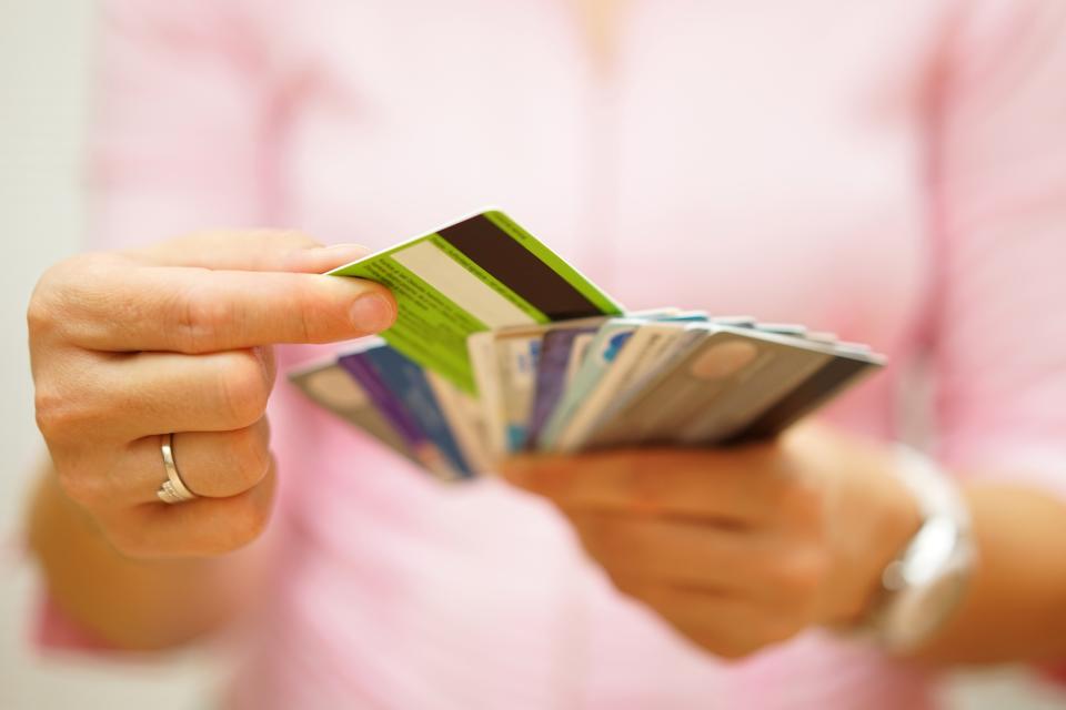 Closeup of a woman's hands shuffling through various credit cards.