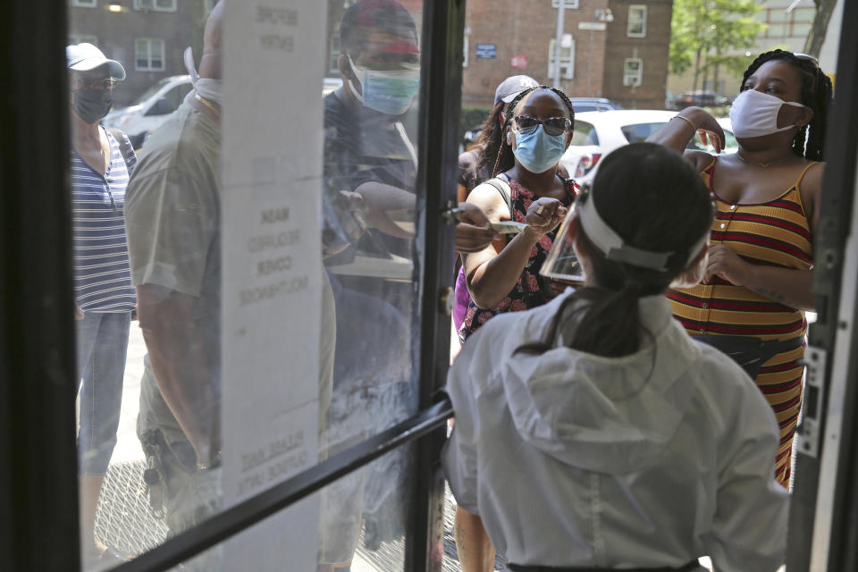 People try to figure out whose appointment is next while talking to an employee at the door of HT&V Nails in the Harlem section of New York, Monday, July 6, 2020. Nail salons and dog runs were back in business on Monday as New York City entered a new phase in the easing of coronavirus restrictions, but indoor restaurant dining will be postponed indefinitely in order to prevent a spike in new infections. (AP Photo/Seth Wenig)