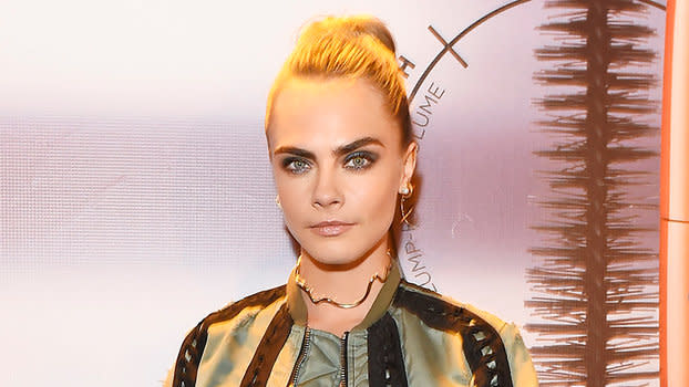 Cara Delevingne flaunts her taut midriff in a funky sports bra at