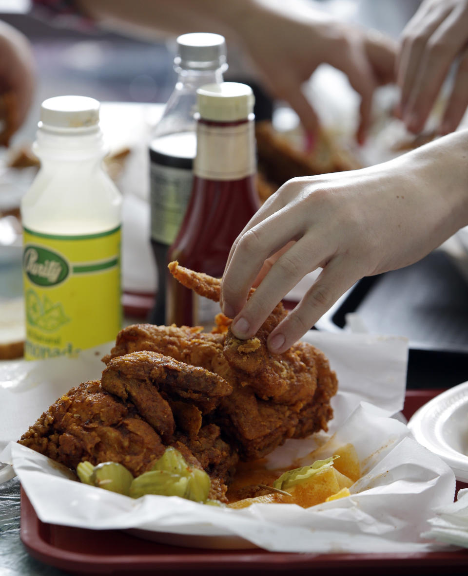 In this Friday, March 23, 2013 photo, a diner reaches for a piece of hot chicken at Prince's Hot Chicken Shack in Nashville, Tenn. Hot chicken -- fried chicken with varied amounts of seasoning that make the heat level run from mild to extra hot -- is a signature dish of Nashville. (AP Photo/Mark Humphrey)