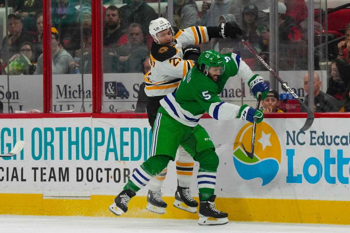 Carolina Hurricanes defenseman Jalen Chatfield (5) checks Boston Bruins right wing Garnet Hathaway (21) during the second period at PNC Arena. James Guillory/USA TODAY Sports