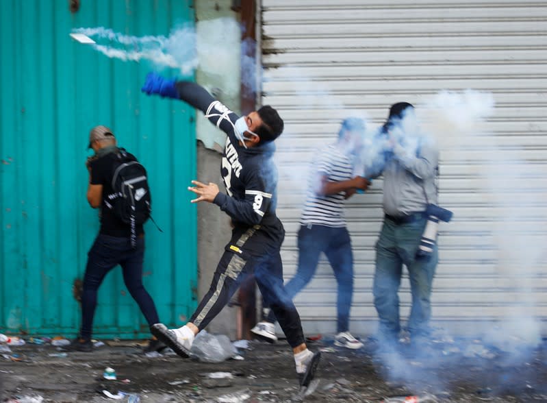 Iraqi demonstrator throws a tear-gas during ongoing anti-government protests in Baghdad