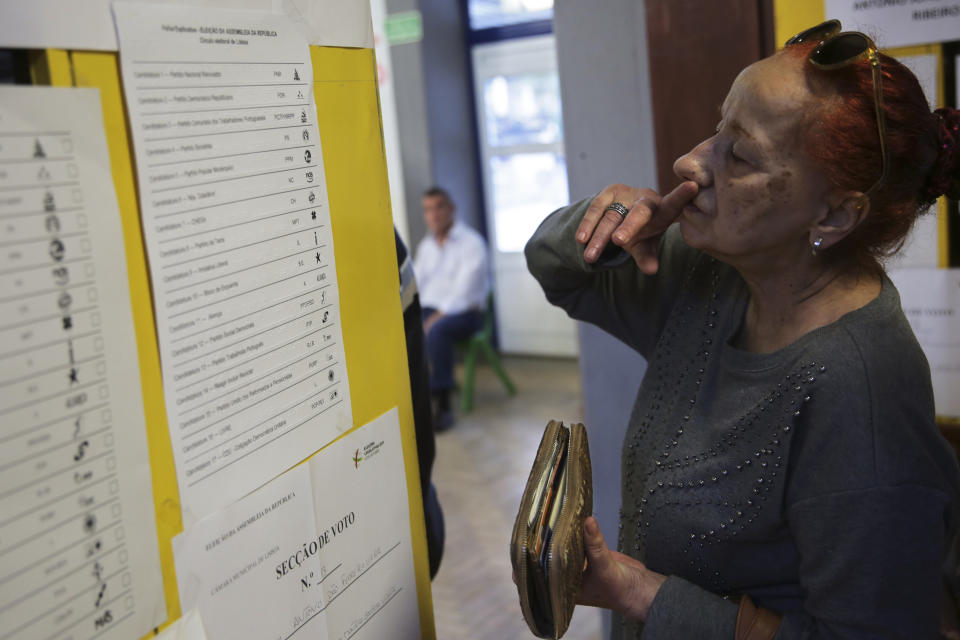 A woman looks at samples of ballot papers before voting at a polling station in Lisbon Sunday, Oct. 6, 2019. Portugal is holding a general election Sunday in which voters will choose members of the next Portuguese parliament. (AP Photo/Armando Franca)