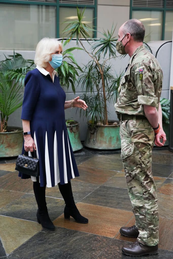 <p>Camilla looked stylish in a navy and white collared dress and black boots during an outing to meet with officials involved in England’s vaccine rollout. She paired the look with a black quilted leather Chanel handbag, one of her frequently featured accessories.</p>