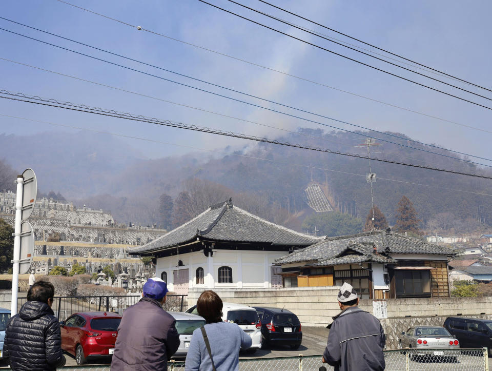 Residents watch as smoke rises from the site of a wildfire in Ashikaga, Tochigi prefecture, north of Tokyo Wednesday, Feb. 24, 2021. A forest fire broke out in the rural area Thursday, near another blaze burning since Sunday, Feb. 21. (Kyodo News via AP)