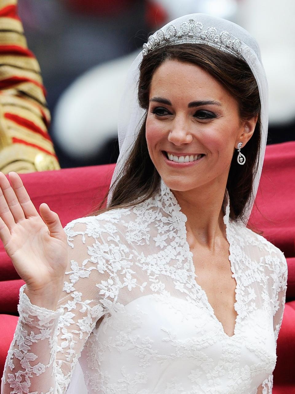 Catherine, Duchess of Cambridge waves as she travels beside husband Prince William, Duke of Cambridge in the 1902 State Landau carriage on the procession route along The Mall to Buckingham Palace after their wedding ceremony at Westminster Abbey on April 29, 2011 in London, England