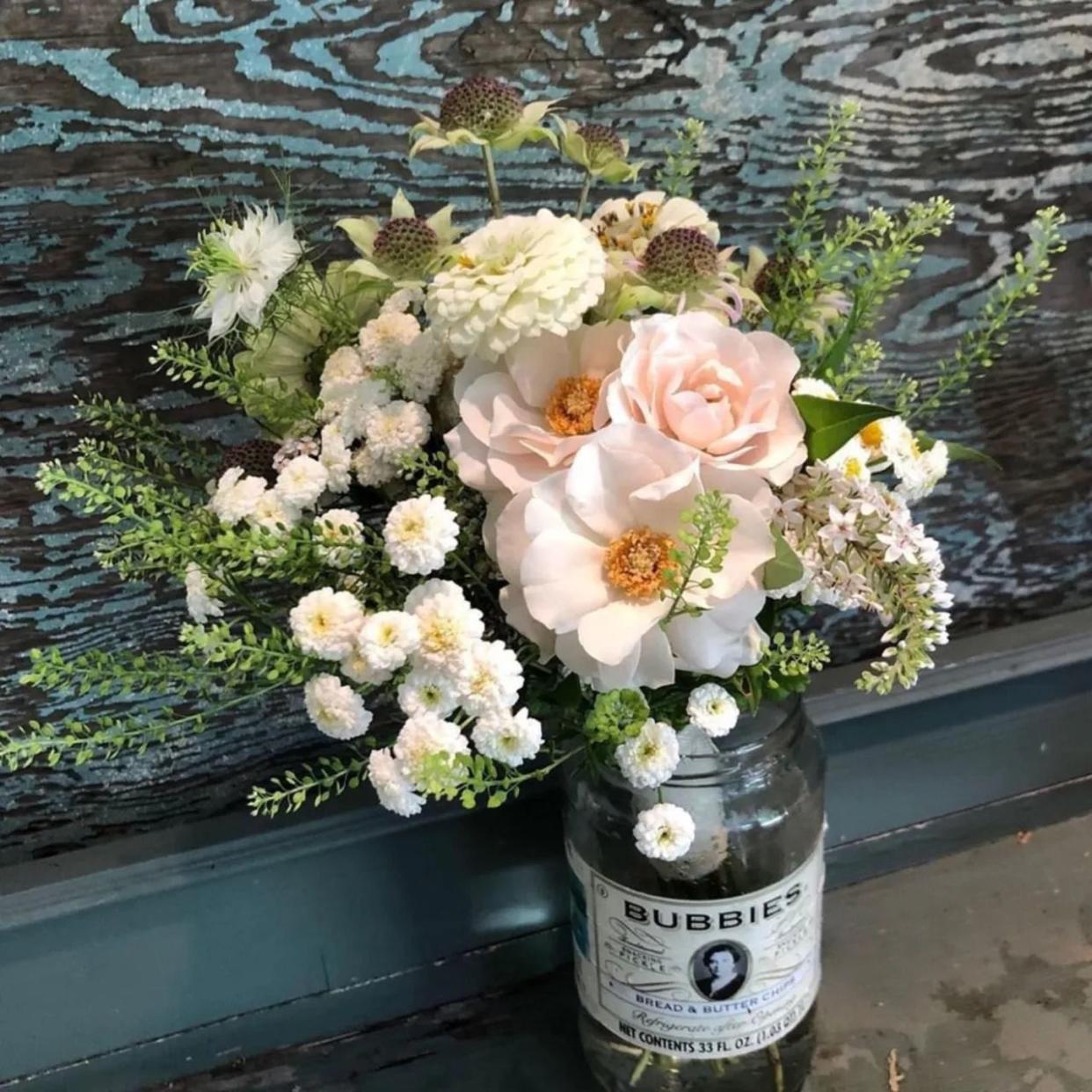 white and soft pink floral arrangement with greenery in upcycled bubbies pickle jar vase