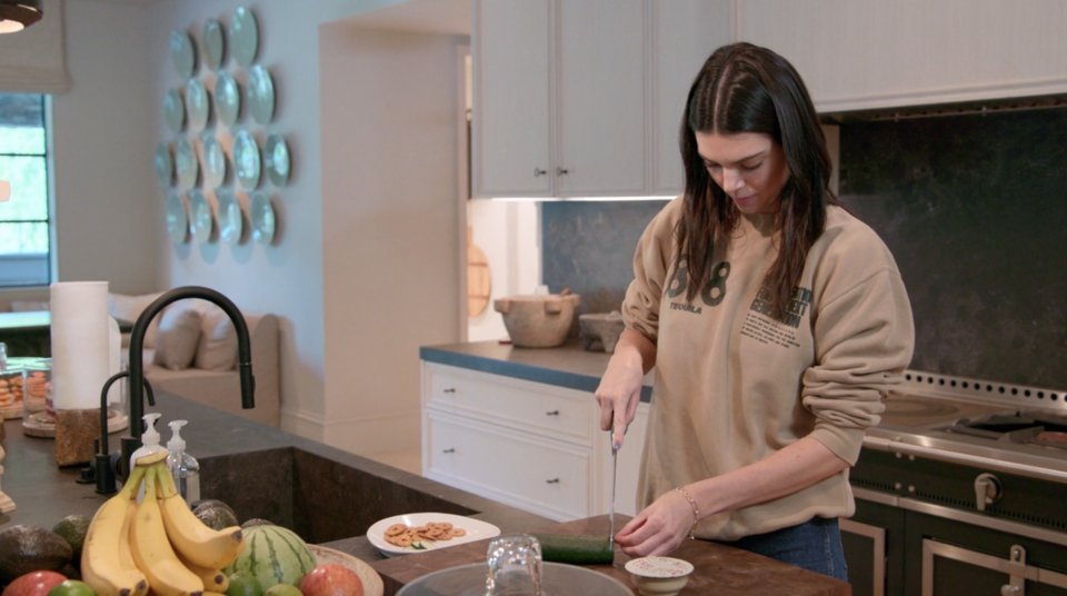Kendall in a kitchen cutting a cucumber
