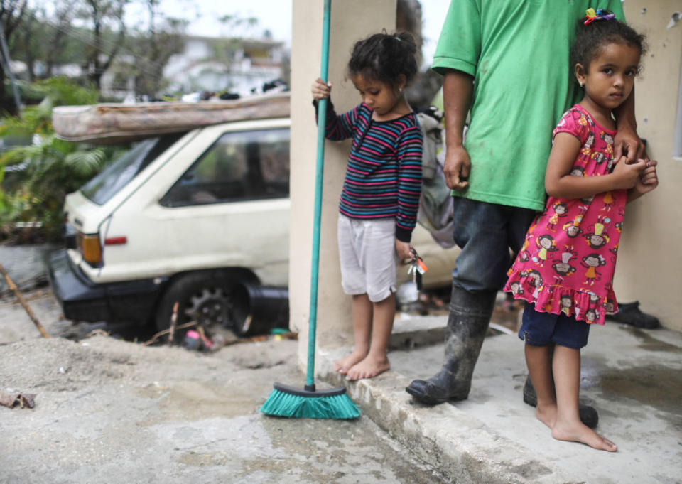 JAYUYA, PUERTO RICO - OCTOBER 09: Young members of the Timoral family stand in front of their damaged home, with no running water or electricity, more than two weeks after Hurricane Maria hit the island, on October 9, 2017 in Jayuya, Puerto Rico. Only 15 percent of Puerto Rico's electricity has been restored. Puerto Rico experienced widespread damage including most of the electrical, gas and water grid as well as agriculture after Hurricane Maria, a category 4 hurricane, swept through. (Photo by Mario Tama/Getty Images)