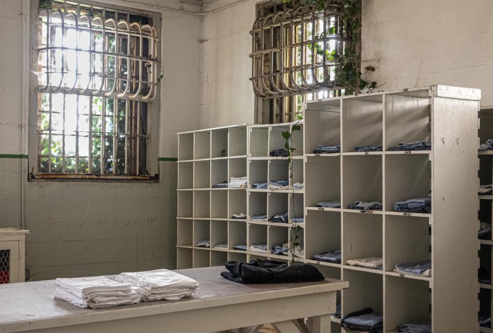 Inside historic Alcatraz prison. Linen and fresh clothing section stacked in cabinet square sections. Heavy metal grids in front of windows.