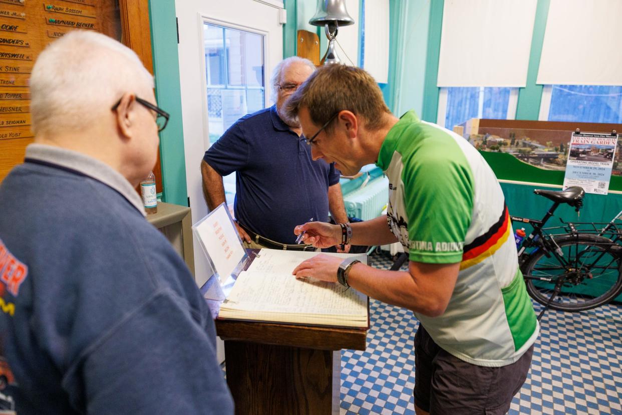 Andreas Beneke, from Hannover, Germany, signs the guest book of the Greater Hanover Area Fire Museum while on a bicycle trip around the world, Friday, April 19, 2024, in Hanover Borough.