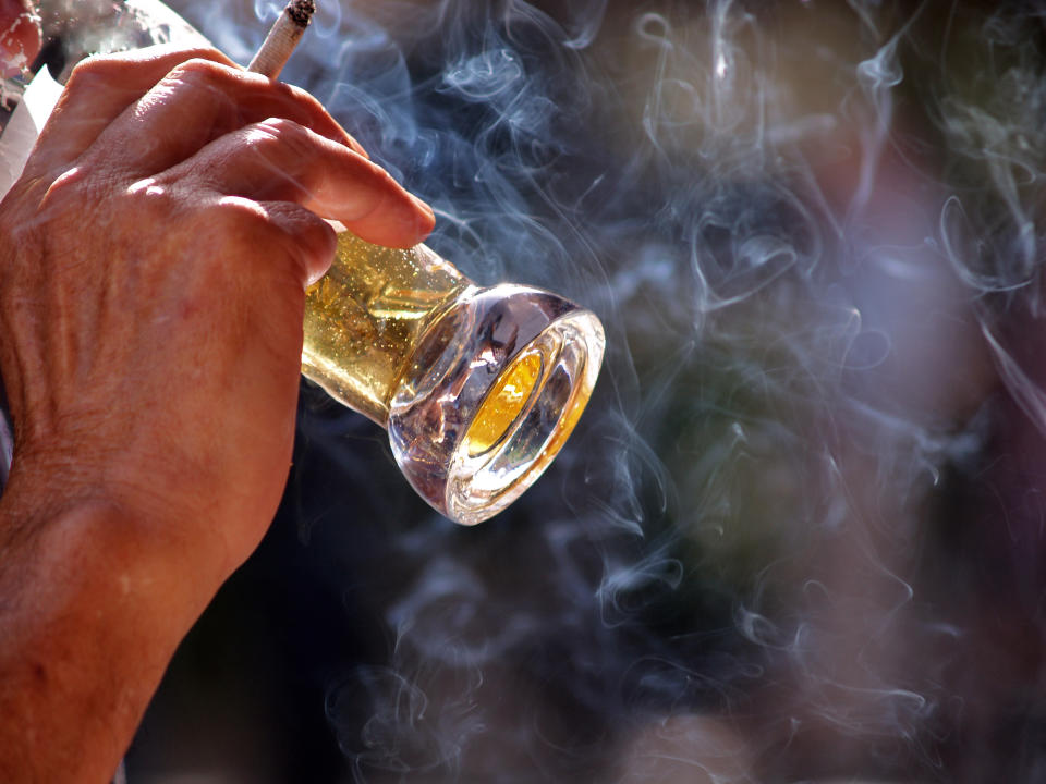 an old man sitting at the table in outdoor pub Drinking beer and smoking