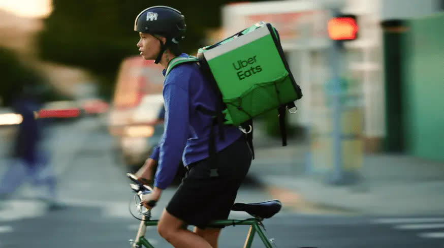 A man riding a bike with an Uber Eats bag.