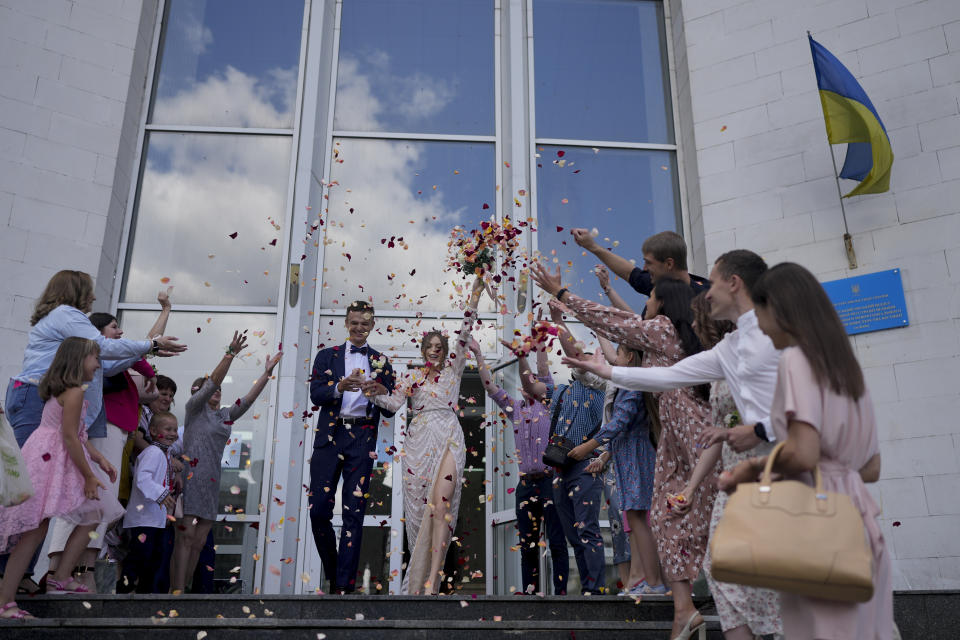 Denys Voznyi and Anna Karpenko leave after getting married in Kyiv, Ukraine, Wednesday, June 15, 2022. A growing number of couples in Ukraine are speedily turning love into matrimony because of the war with Russia. Some are soldiers, marrying just before they head off to fight. Others are united in determination that living and loving to the full are more important than ever in the face of death and destruction. (AP Photo/Natacha Pisarenko)