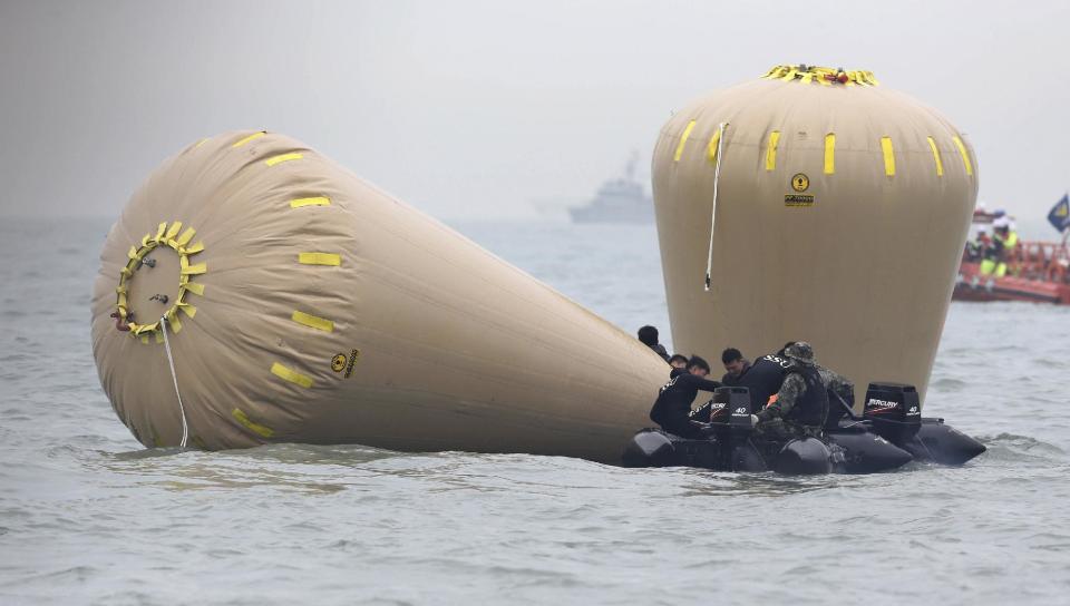 South Korean navy personnel try to install buoys to mark the sunken passenger ship Sewol in the water off the southern coast near Jindo, South Korea, Friday, April 18, 2014. Rescuers scrambled to find hundreds of ferry passengers still missing Friday and feared dead, as fresh questions emerged about whether quicker action by the captain of the doomed ship could have saved lives. (AP Photo/Yonhap) KOREA OUT