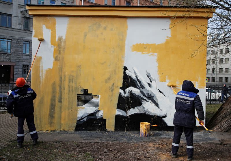 Workers paint over a graffiti depicting Alexei Navalny in Saint Petersburg