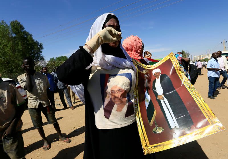 A supporter of Sudanese former president Omar Hassan al-Bashir carries his picture during a protest outside the court house that convicted him on corruption charges in Khartoum