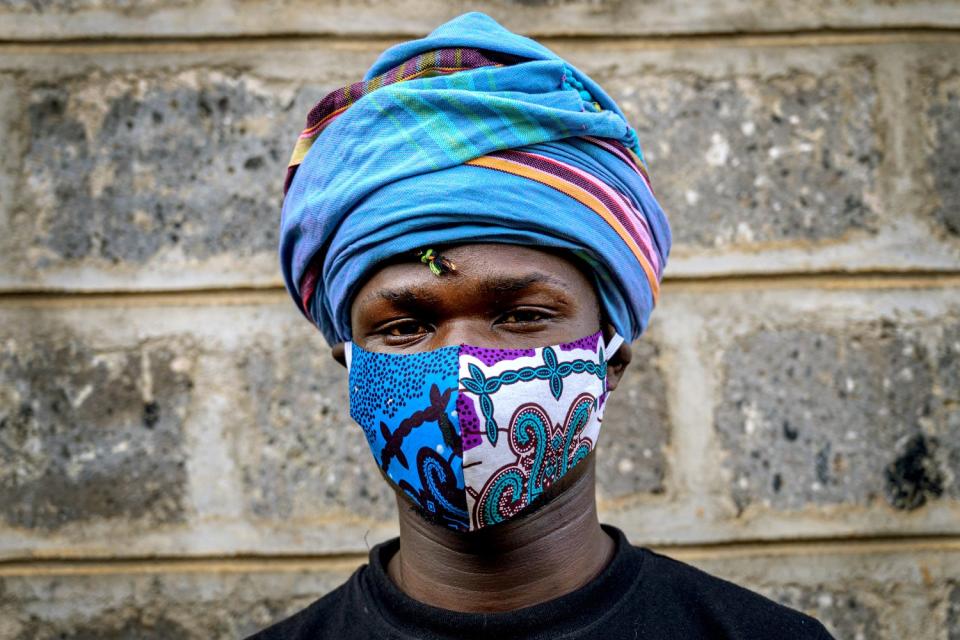 KENYA: Fashion designer David Avido, 24, poses for a portrait at his studio in Nairobi with a mask he made from remnants of cloth.