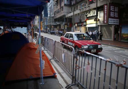A taxi drives past tents at a protest site after police removed some barricades, at the commercial area of Causeway Bay in Hong Kong October 14, 2014. REUTERS/Carlos Barria