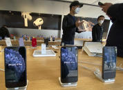 In this photo taken Wednesday, Feb. 19, 2020, staff chats with customers at an apple store in Beijing. Factories that make the world's smartphones, toys and other goods are struggling to reopen after a virus outbreak idled China's economy. But even with the ruling Communist Party promising help, companies and economists say it may be months before production is back to normal. (AP Photo/Ng Han Guan)